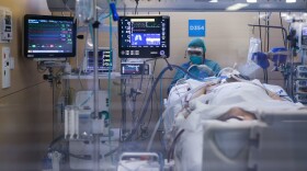A health care worker wearing a protective suit attends to a coronavirus patient at the intensive care unit. (Pau Barrena/AFP via Getty Images)