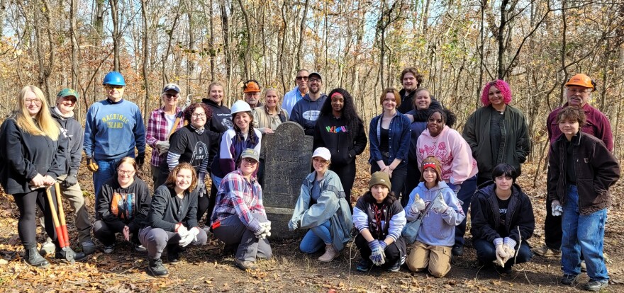 A group of volunteers stand by a headstone in the Miller Grove Cemetery in Pope County after helping cleanup the area.