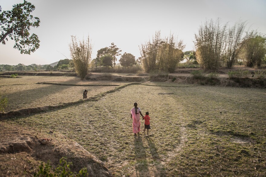 Seteng Horo and her son, Abishiek, walk toward her husband, Kunwar, who's working in the fields.