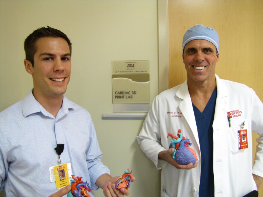 Justin Ryan and Dr. Stephen Pophal stand outside the Cardiac 3-D Print Lab holding heart models for the Cardiac Library at Phoenix Children's Hospital.