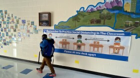 A Cotswold Elementary student walks past a social distancing banner on the way to class Monday.