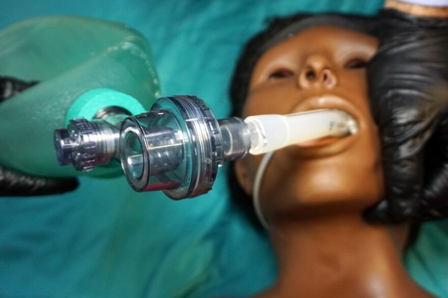 Anesthesiologist in a black gloves performing an orotracheal intubation on a simulation mannequin dummy during medical training to control of the airway.