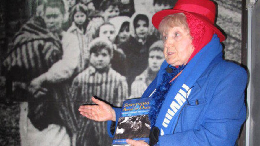 Eva Kor showing a picture of herself on the wall at the Auschwitz concentration camp.
