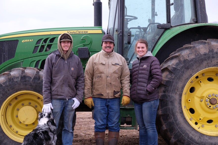 Jay Peterson (center), a fourth generation rancher, stands with his son Ty (left) and daughter Hailey (right) in front of their tractor as they take a break from working at the ranch on March 5, 2022.