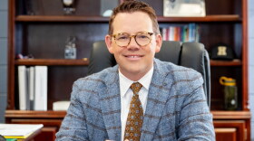 A headshot of Dale Cole, the new superintendent of Brunswick County Schools. He is a white man in his forties with short brown hair and horn-rimmed glasses. He is smiling at the camera while posed sitting at his desk. 