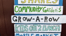 Colorful sign listing program offerings of a food program including "shares" "grow-a-row" and "composting"