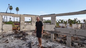 The Rev. Ai Hironaka looks down at his former temple and residence, the Lahaina Hongwanji Mission, destroyed in the 2023 wildfires, Sunday, July 7, 2024, in Lahaina, Hawaiʻi. Hironaka escaped the wildfire with his family but lost his temple and all their belongings in the blaze. He now lives across the island at Kahului Hongwanji Mission, serving as resident minister. He performs much of the same work he did at the Hongwanji Mission in Lahaina: leading ceremonies and counseling members, including fire survivors.