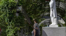 A woman poses in front of a decapitated statue of Christopher Columbus viewed at Christopher Columbus Park in Boston Massachusetts on June 10, 2020. 