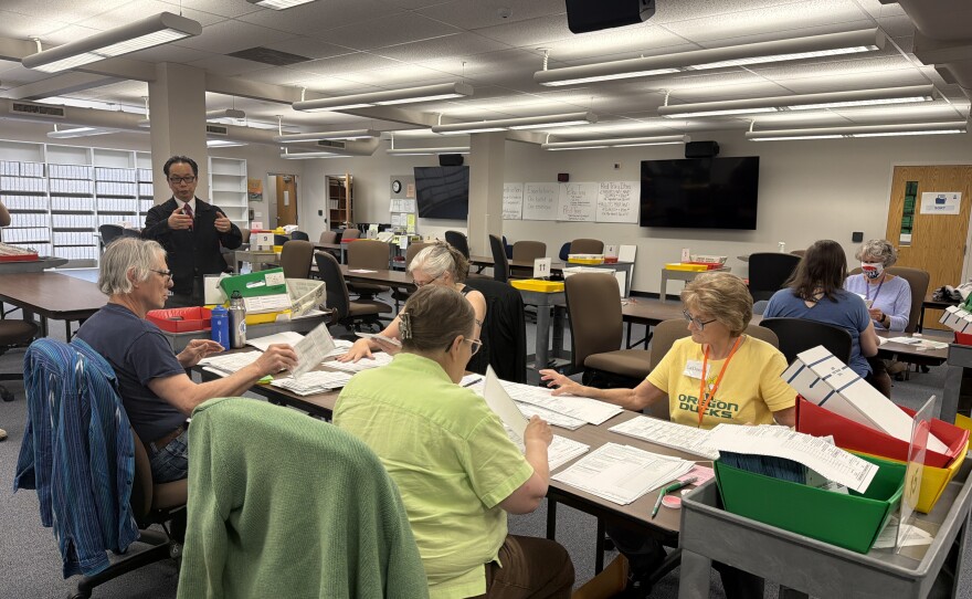 A group of Lane County Elections Office employees remove ballots from their envelopes and unfold them, preparing them to be scanned for vote counting, May 15, 2026.