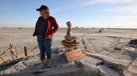 Candace Youngberg stands on the remains of what was once a waterfront pier by the receding shoreline of the Salton Sea in Bombay Beach, Calif., on Friday, Dec. 15, 2023. The water’s edge reached the pictured fountain in 2011.