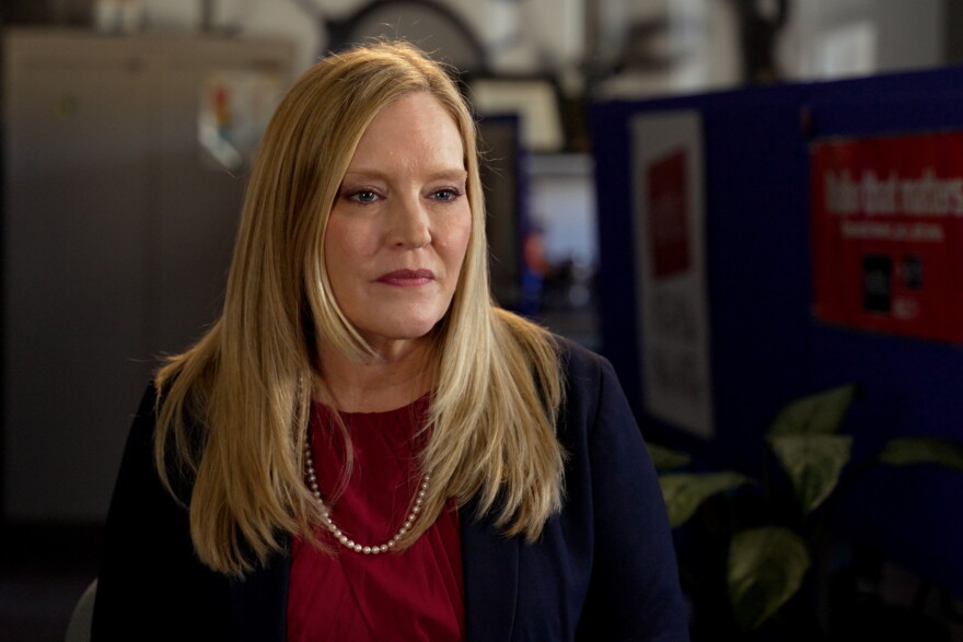 A blonde woman sits in a room.