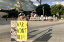 Demonstrator Lola La Fey holds a sign showing damage her home sustained from Hurricane Helene as she stands near Pack Square in Asheville on Friday, August 28, 2026.
