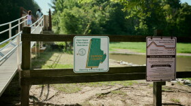 A sign on a fence in front of a river