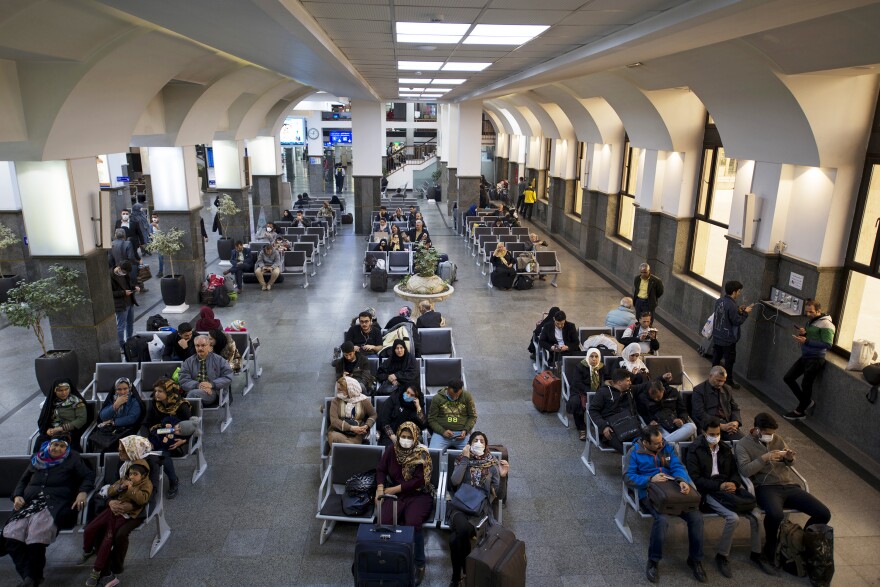 People sit in the main waiting area in Tehran's railway station. Crews of cleaners were dispatched to disinfect trains, buses and public gathering places.