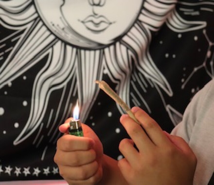 Someone lights a joint in the living room of their apartment.