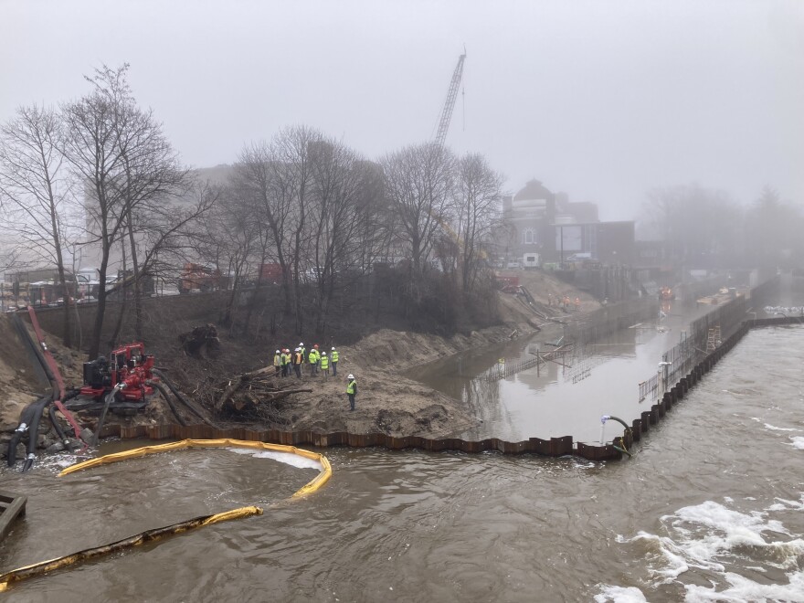 A group of contractors assesses the situation at FishPass in the Boardman-Ottaway River on Tuesday morning. A retaining wall above the construction site collapsed, sending runoff from rain into the cofferdam, which was previously dry. A representative for FishPass says crews are working to pump water out of the cofferdam and that construction materials like rebar and dimensional lumber will still be usable. (Photo: Ellie Katz/IPR News)