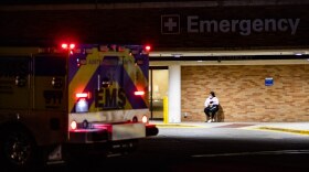 A person wearing a mask waits outside St. David's Medical Center in Austin.