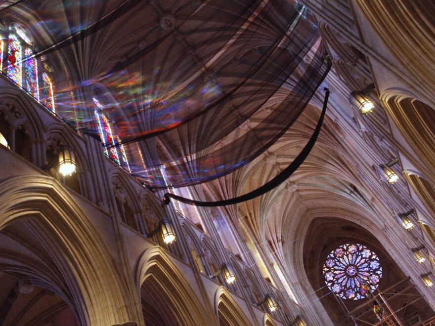 Light from stained glass windows shines onto safety nets that have been installed along the ceiling of the nave at the National Cathedral, as a precautionary measure after parts of the structure was damaged in an earthquake.