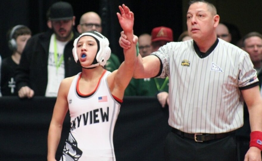 Jaslynn Gallegos (left) stands after winning a match at Colorado's state wrestling championship.