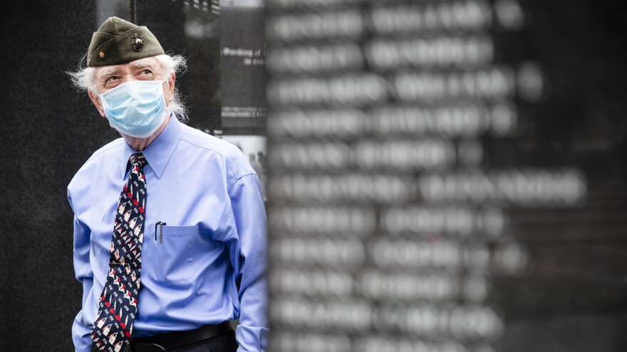 A U.S. Marine Corps veteran pays his respects at the Korean War Memorial behind a face mask in Philadelphia.