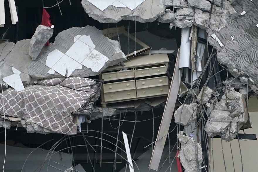 A bed and a chest of drawers dangle from the ruins on Thursday.