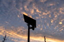 looking up at a ALPR with dramatic orange streak and other orange sports in the dusk sky