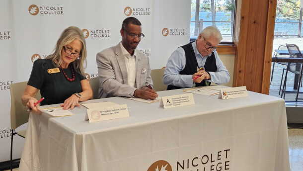 Nicolet College President Kate Ferrell, Director of the Wisconsin Bureau of Apprenticeship Standards David Polk, and Sokaogon Chippewa Community Chairman Robert VanZile sit at a table at the college signing an agreement that will launch a Broadband Service Technician apprenticeship program.