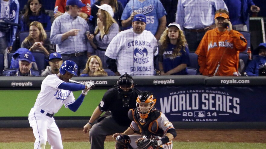 Miami Marlins fan Laurence Leavy (rear right) is shown wearing a bright orange Marlins jersey during a 2014 World Series game in Kansas City. Leavy's orange Marlins jersey made him easy to spot amid a sea of Kansas City Royals blue. He said that a Royals official approached him offering to move him to the team owner's suite, but that he declined.
