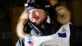 A man with curly hair in a parka with a fur ruff
