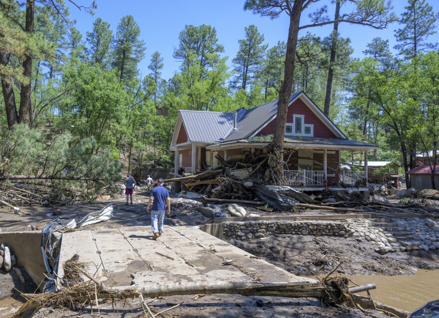 Residents of the town of Ruidoso, N.M., walk back to their neighborhood to find what's left of their homes a day after major flooding washed away properties leaving streets clogged with mud and debris, along the Rio Ruidoso, Wednesday, July 9, 2025, in Ruidoso, N.M. (AP Photo/Roberto E. Rosales)