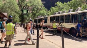 A photo of people in front of a Zion shuttle.