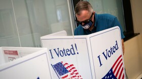 A man wears a face mask featuring the seal of Virginia as he fills out his ballot at an early voting site in Arlington, Virginia, U.S., September 18, 2020.