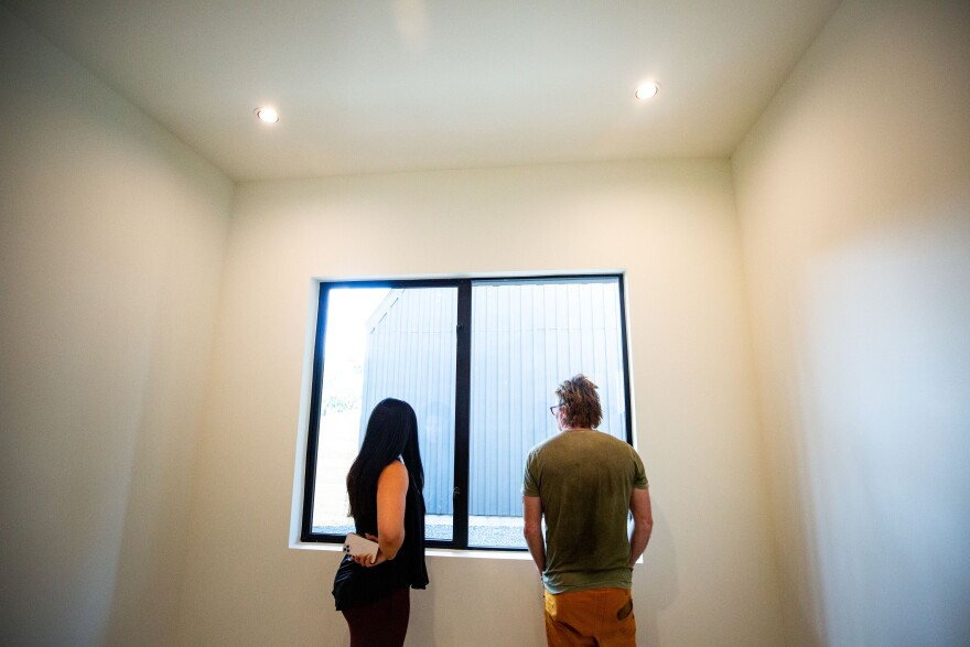 Two people look out a window in a home under construction.