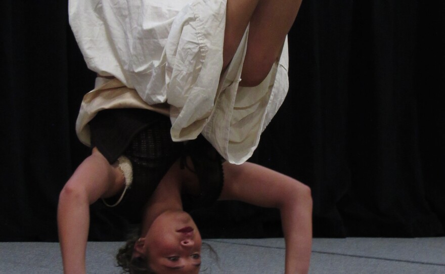 A young girl stands on her head with her knees bent