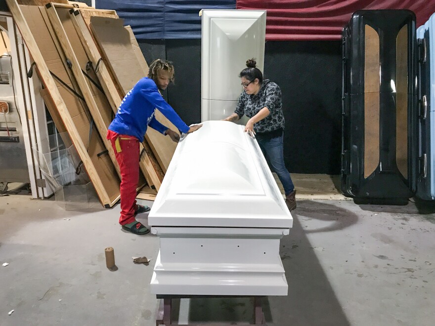 Kenneth Burnett and Maggie Rivera sand a casket, readying it for a pink camouflage paint job at the shop in Edna, Texas. The woman it is for loved to hunt.