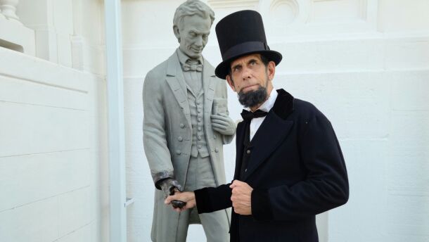Lincoln portrayer Mark Rehagen shaking hands with the new statue of Lincoln.