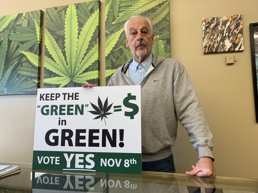 Stephen Ezell holds one of his campaign signs in his store, Interlochen Alternative Health, a medical marijuana dispensary in Green Lake Township. He's hoping voters there approve recreational marijuana sales.