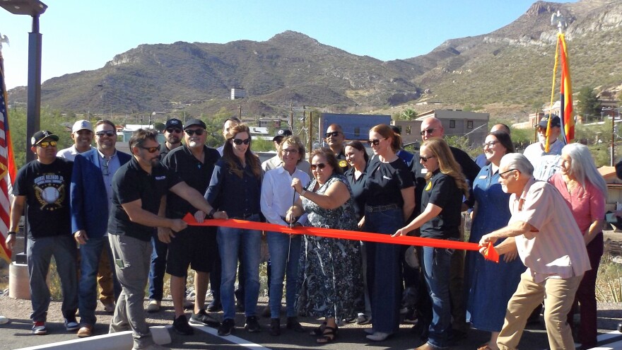 A group of people cut a large ribbon in front of a mountain range