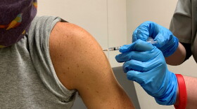 A pharmacist administering a booster dose of a COVID-19 vaccine.