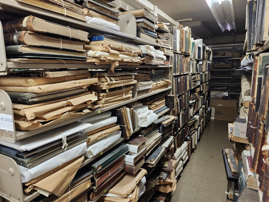 Many old books and files sit on shelves.