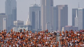 The Dallas skyline rises behind the Cotton Bowl stands as Texas fans watch during the first half of an NCAA college football game against Oklahoma at the Cotton Bowl, Saturday, Oct. 8, 2022, in Dallas. U.S. metropolitan areas increased their populations by almost half a percent last year in another sign that flight from urban areas during the first year of the pandemic either slowed down or reversed in its second year as people moved to Sunbelt metros in Texas and Florida by the tens of thousands.