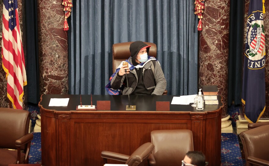 A rioter sits in the Senate Chamber.