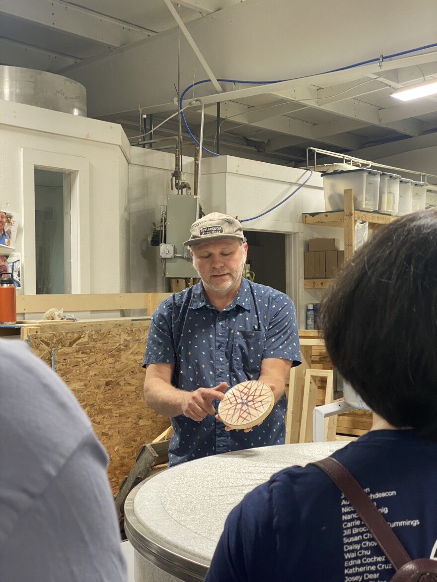 Andrew Hayes shows the tour how a stone mill works using a hand-held wooden model 