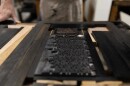 Gary Gregory at Haverhill’s Museum of Printing demonstrates the printing process with a replica of 18th-century press. Metal blocks of type like these were dabbed with ink then pressed onto paper to print early American newspapers.