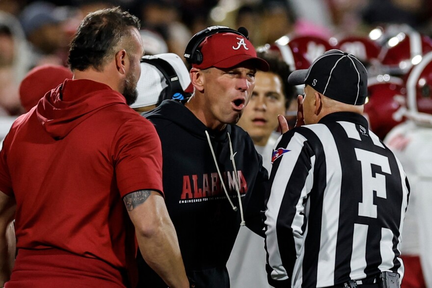 Alabama head coach Kalen Deboer, center, speaks with an official during the first half in the first round of an NCAA College Football Playoff against Oklahoma, Friday, Dec. 19, 2025, in Norman, Okla. (AP Photo/Alonzo Adams)