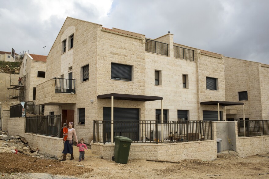 An Israeli settler and her two children leave a friend's house in a new housing development under construction in Ariel, West Bank.