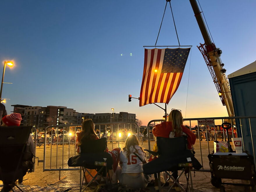 Crews raise an American flag to mark the start of the parade route at 6th and Grand in Kansas City on Feb. 14, 2024.