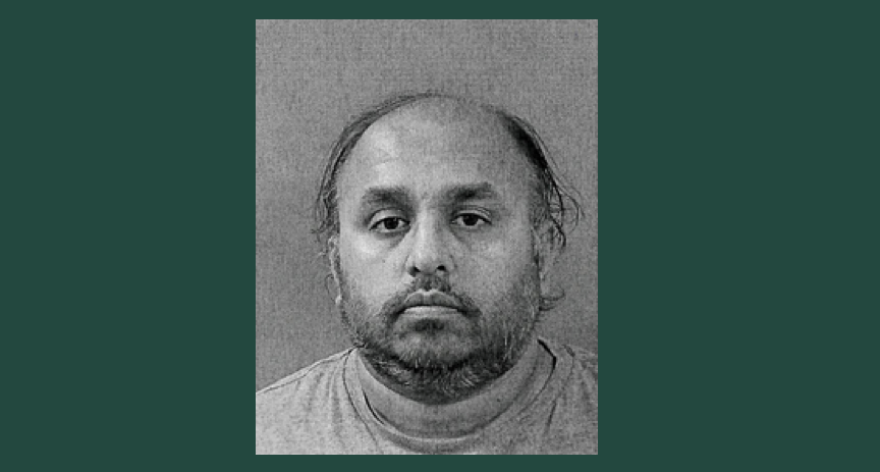 A black-and-white mugshot on a dark green background