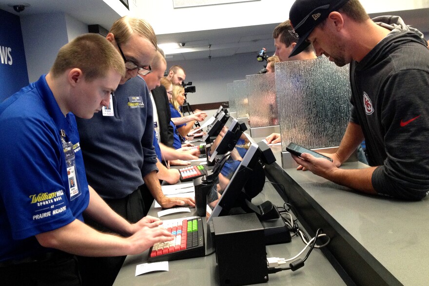 Workers at Prairie Meadows in Altoona, Iowa, take the first bets at the casino's new sportsbook.