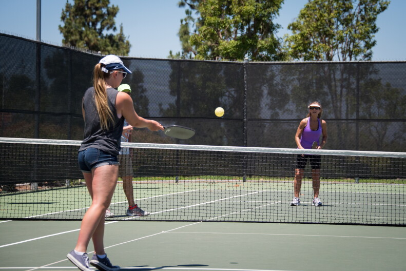 A family plays pickle ball together on a court.